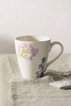 a coffee cup sitting on top of a table next to a spoon and napkins