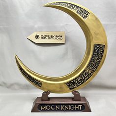 a gold and black moon with arabic writing on the front is shown against a white background