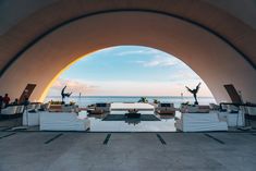 an outdoor area with couches and tables overlooking the ocean