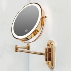 a mirror mounted to the side of a white wall next to a gold hook on a door