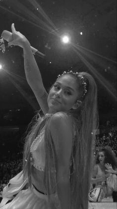 a black and white photo of a woman with long hair sitting on the floor in front of an audience