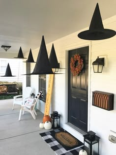 the front porch is decorated for halloween with black and white decorations, pumpkins, and witches hats