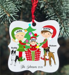 a christmas ornament hanging from a tree with two children and a dog on it