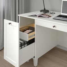 a white desk with a laptop on it and some files in the drawer under the desk