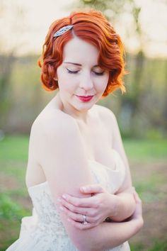 a woman with red hair wearing a white dress and holding her arm around her chest