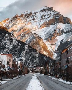 a snow covered mountain is in the distance with buildings on both sides and street lights at the bottom