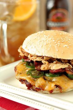 a sandwich with meat, cheese and vegetables on a white plate next to a drink