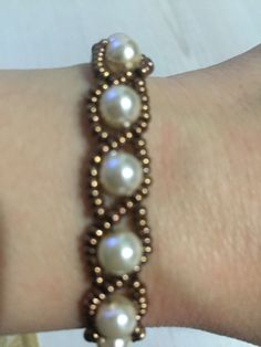 a close up of a person's arm wearing a bracelet with pearls on it