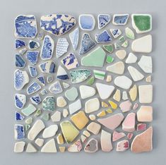 a piece of art made out of various pieces of glass and stone, on a gray surface