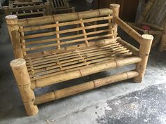 a wooden bench made out of bamboo sticks and other wood furniture in a room filled with chairs