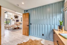 a living room filled with furniture next to a wooden table and wall covered in blue paneling