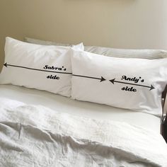 two pillows that have arrows on them in the middle of a bed with white sheets