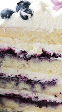 a close up of a slice of cake with blueberries and cream frosting on it