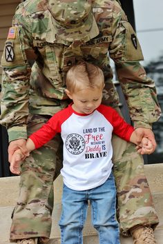 a little boy is sitting on his father's lap while he wears a t - shirt that says land of the free