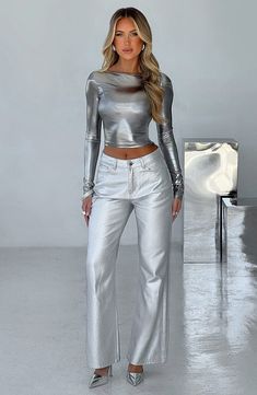 a woman in silver pants and top posing for the camera with her hands on her hips