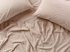 an unmade bed with white sheets and pillows