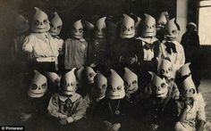 an old black and white photo of children wearing weird looking hats with faces on them