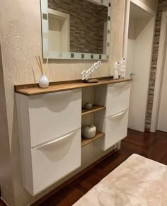 a bedroom with a bed, dresser and mirror in the corner next to a brick wall