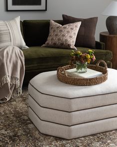 a living room filled with furniture and pillows on top of a carpeted floor next to a green couch