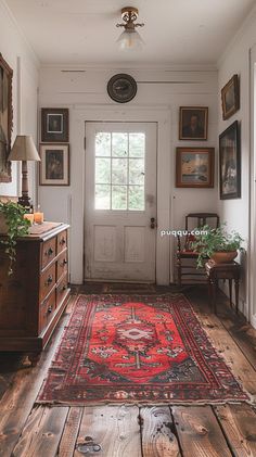 a red rug is on the floor in front of a white door with framed pictures