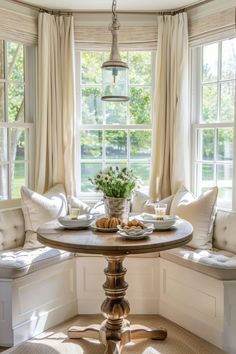 a breakfast nook in the corner of a room with two windows and a bench