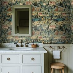 a bathroom with a vanity, mirror and wall papered in forest designs on the walls