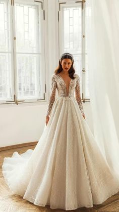 a woman in a wedding dress standing by a window