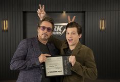 two men standing next to each other holding up an award for best performance in a musical play