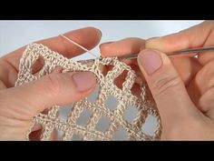 two hands crocheting together to make a small piece of fabric with yarn on it