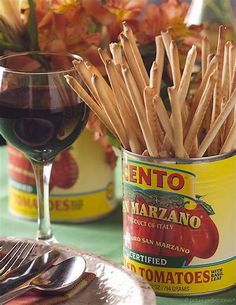 there is a glass of red wine and some wooden sticks in a tin on the table