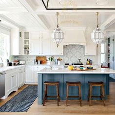 a large kitchen with white cabinets and blue island counter tops, along with two stools