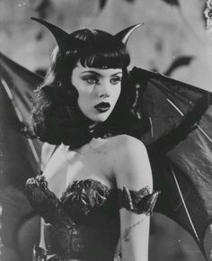 a woman dressed in devil makeup holding an umbrella