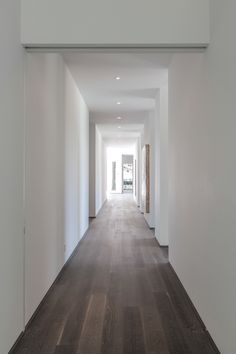 an empty hallway with white walls and wood floors is seen in this image from the inside