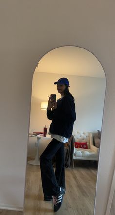 a woman taking a selfie in the mirror with her cell phone and hat on