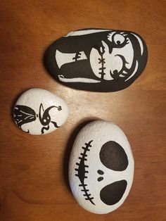 three painted rocks sitting on top of a wooden table