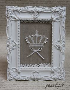 a small white frame with a crown on the front and two swords in the middle