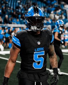 a football player wearing a black uniform and blue numbers on his face is walking off the field