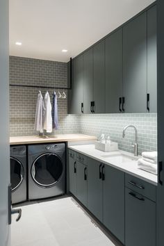 a washer and dryer in a room with grey cabinets, white counter tops