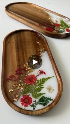 two wooden trays with flowers and leaves painted on the sides, one is empty