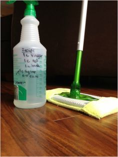 a bottle of cleaner next to a mop on a wooden table