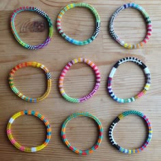 six different colored bracelets sitting on top of a wooden table