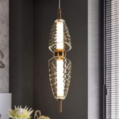 two glass lights hanging from the ceiling in a room with grey walls and white flowers