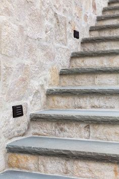 there is a set of stairs leading up to the top of this stone building with black numbers on it