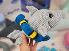 a hand is holding a crocheted toy shark