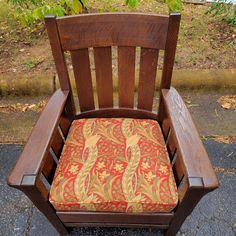 a wooden chair with a red and gold cushion on top of it's seat