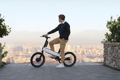 a man is riding an electric bike in front of a cityscape and mountains