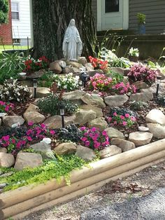 a garden with rocks and flowers in front of a house