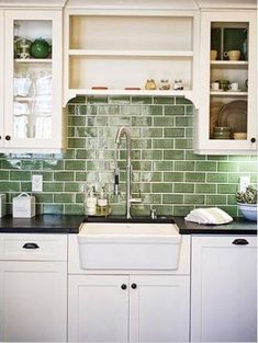 a kitchen with white cabinets and green tile backsplash