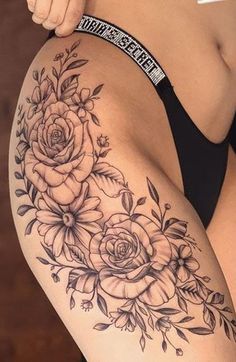 a woman's thigh with roses and leaves on the side, in black and white