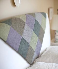 a close up of a bed with pillows and blankets on top of the headboard